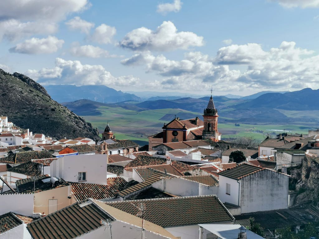 Discover the charming rooftops and majestic church in Cañete la Real, Spain, against a mountainous backdrop.