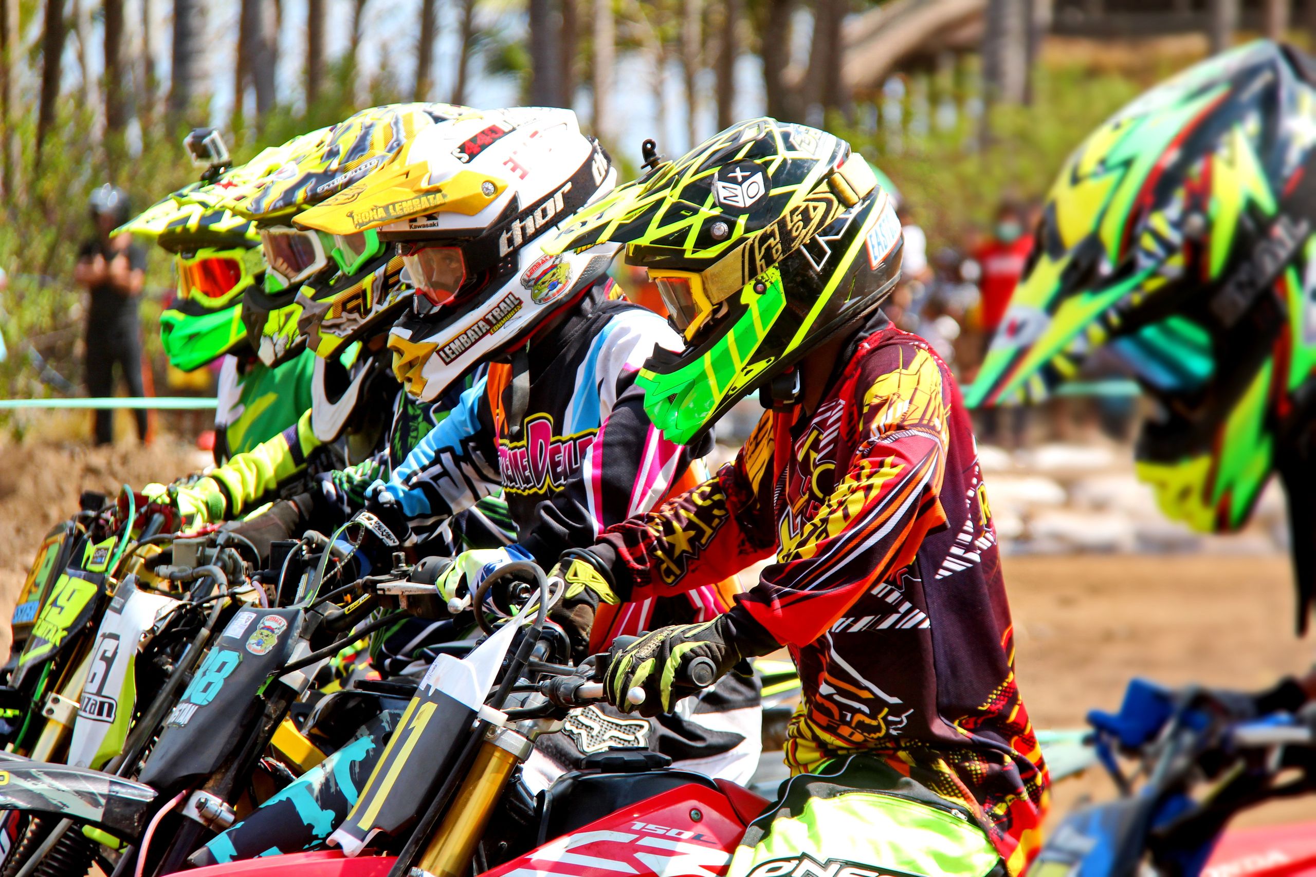 Motocross riders in vibrant gear prepare for a thrilling race outdoors.