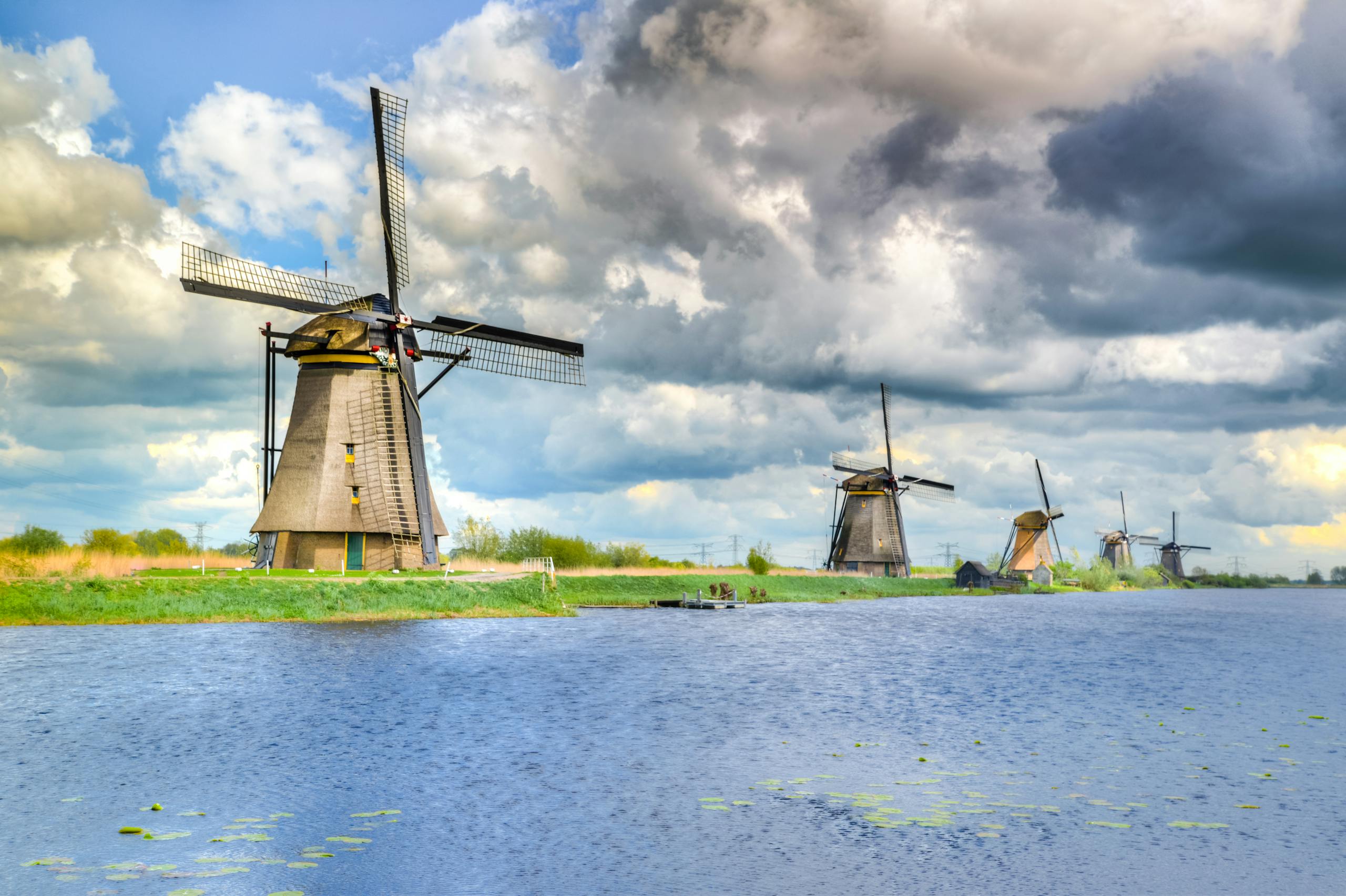 Picturesque view of historic Dutch windmills on a cloudy day by the water.